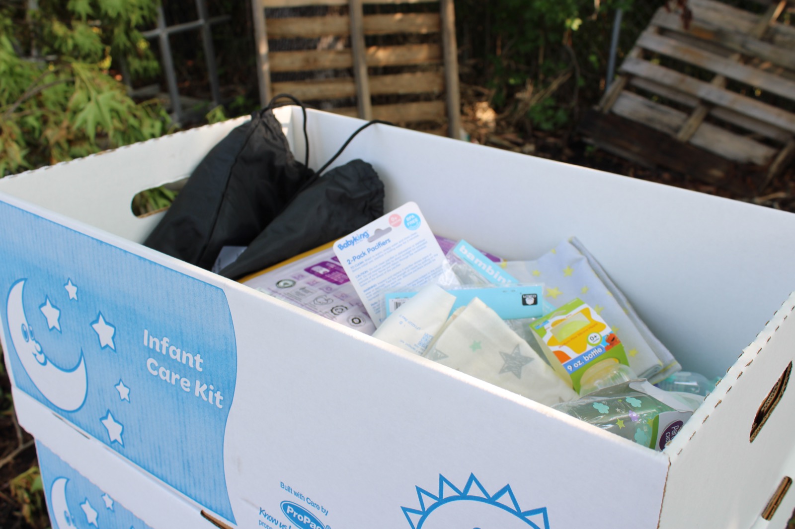 An open Infant Care Kit box showing pacifiers, wipes, bottles, and other infant supplies.