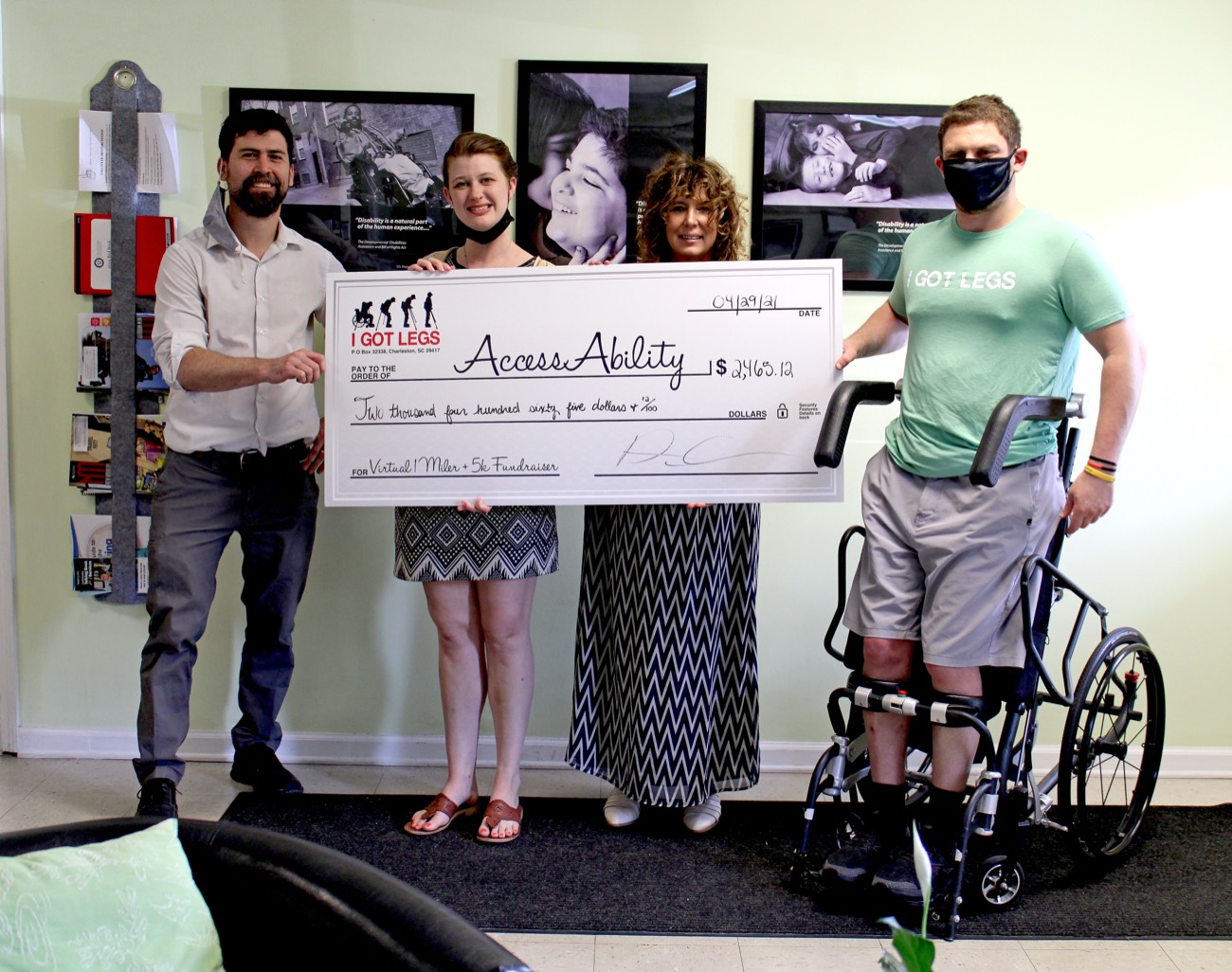 AccessAbility supporters at a check presentation, with a wheelchair in the foreground.