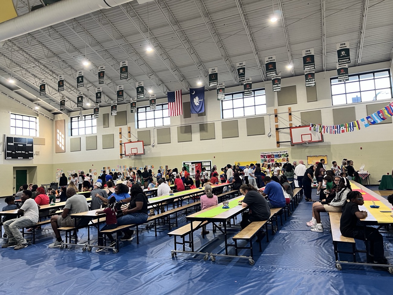 A packed AccessAbility community event with people gathered at tables in a large hall.