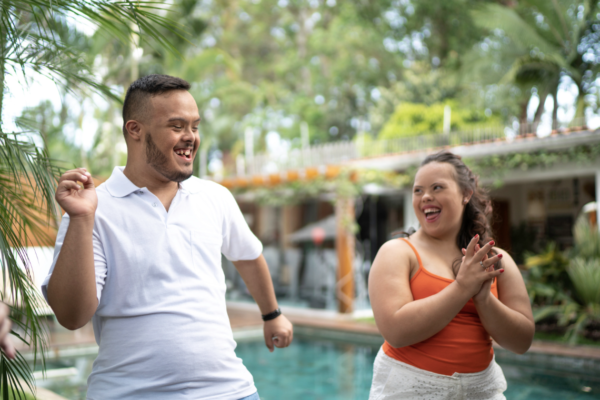 Two young adults outside dancing with each other while smiling.