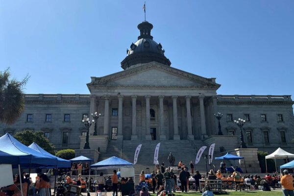 People standing outside the front lawn of the state capital to show support for Advocacy Day and disability rights.