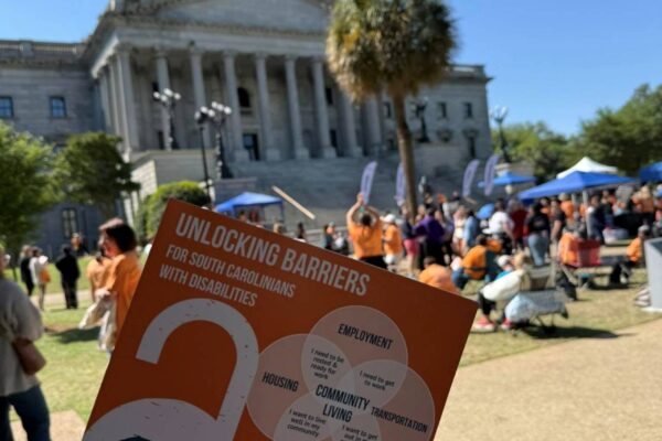 An informational hand held fan being held up in front of the south carolina state capital in columbia.