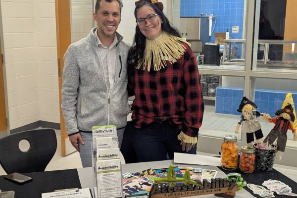 Jason and Tammy from AccessAbility working a table at a transition fair. Tammy is dressed as a scarecrow.