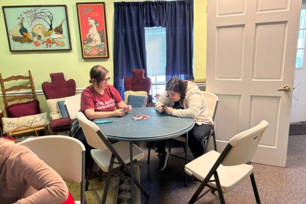 Megan from AccessAbility and a LIT member sitting at a round table playing Uno.