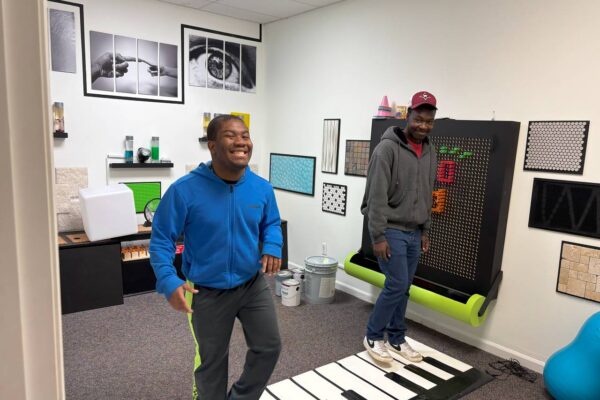 LIT members using the foot piano in the music room at Scotty's Place.