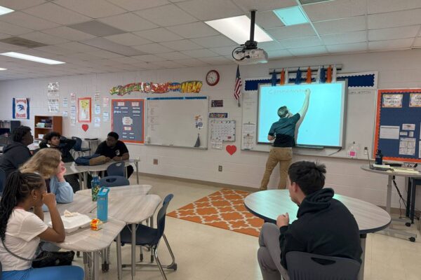 J from AccessAbility teaching in a classroom to a group of students.