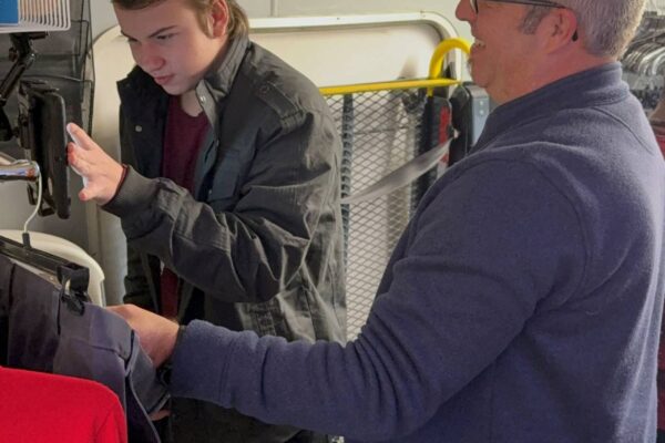 Tony from AccessAbility showing a student how to select a piece of clothing for processing on Big Benny.