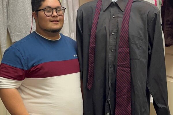Attendee posing with an outfit he picked out and placed on a mannequin.