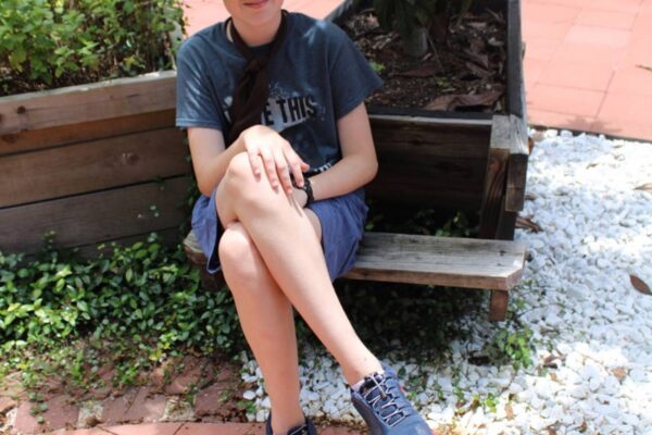 Attendee posing in the sensory garden sitting next to a planter.