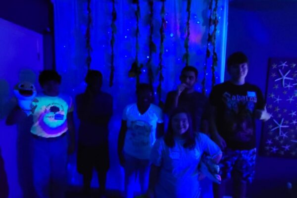 Summer session attendees hanging out in the ocean room with the black lights on.