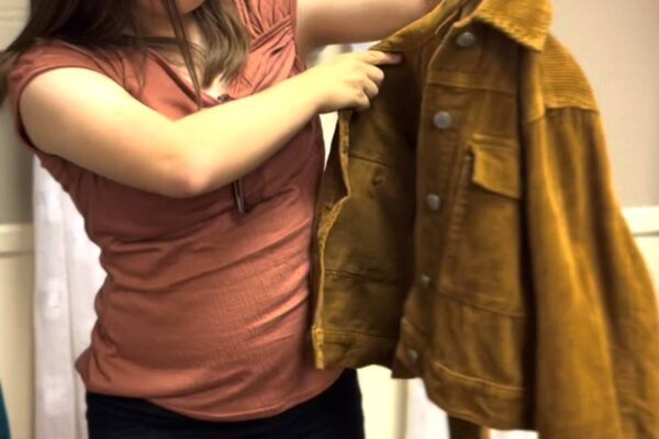 Kayla posing with a brown button up jacket that she selected for her sales pitch feature.