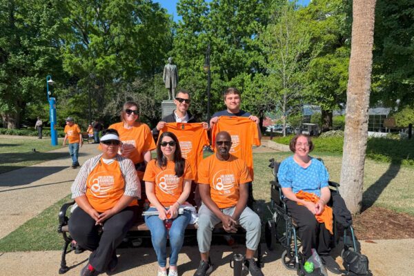 The AccessAbility team sitting on a bench posing for a picture during Advocacy Day outside the state capital in columbia south carolina.